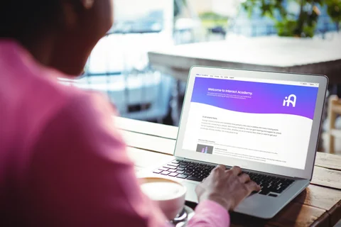 hand on laptop keyboard with Interact Academy homepage